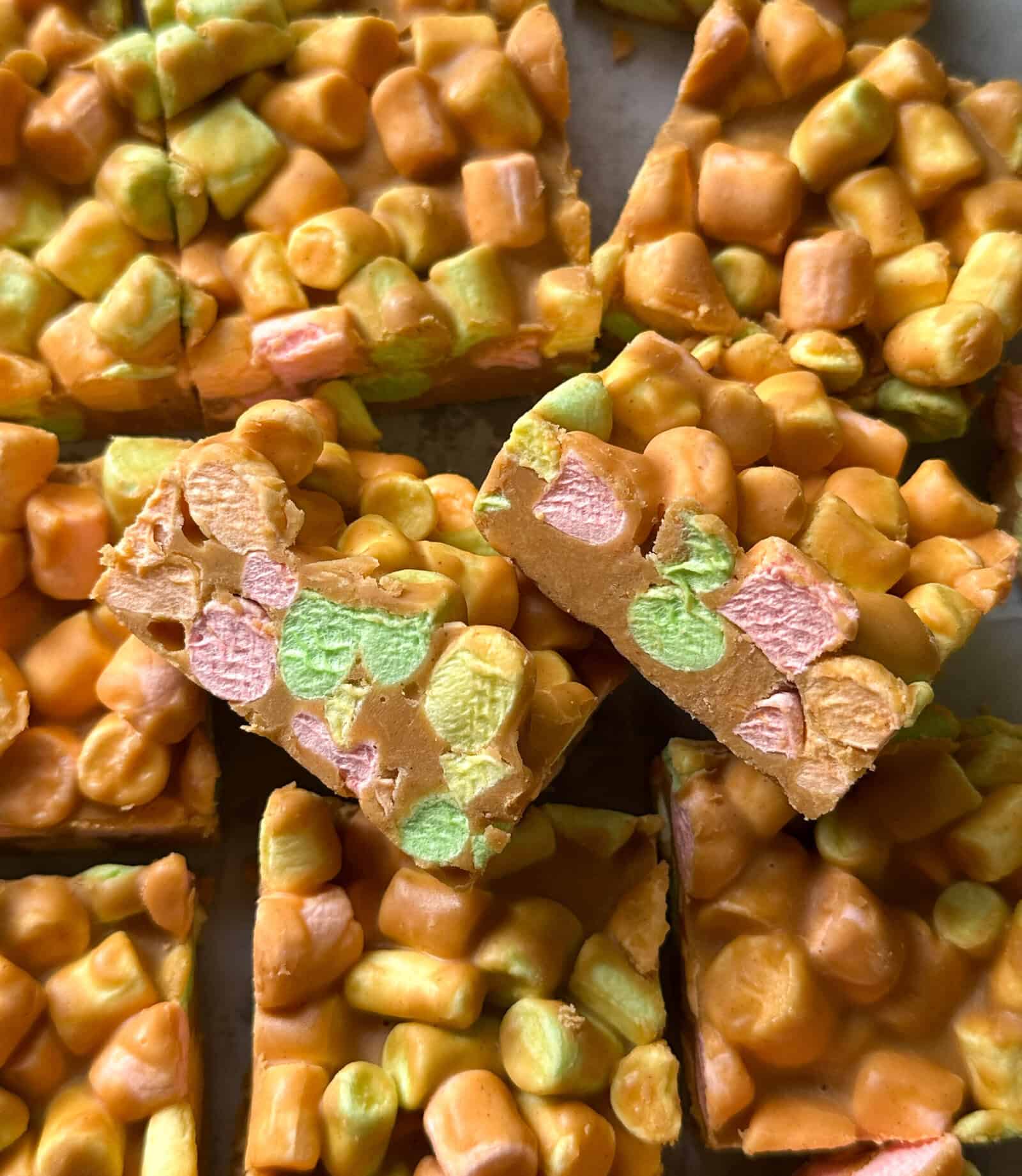 Close-up of colorful peanut butter marshmallow squares, featuring mini pastel marshmallows coated in a glossy orange mixture—an easy no bake dessert everyone will love.