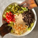 A bowl of Big Mac salad featuring chopped lettuce, diced tomatoes, shredded cheese, pickles, cooked ground beef, and creamy dressing in the center, with two wooden salad forks resting on the rim—a classic Big Mac salad recipe.