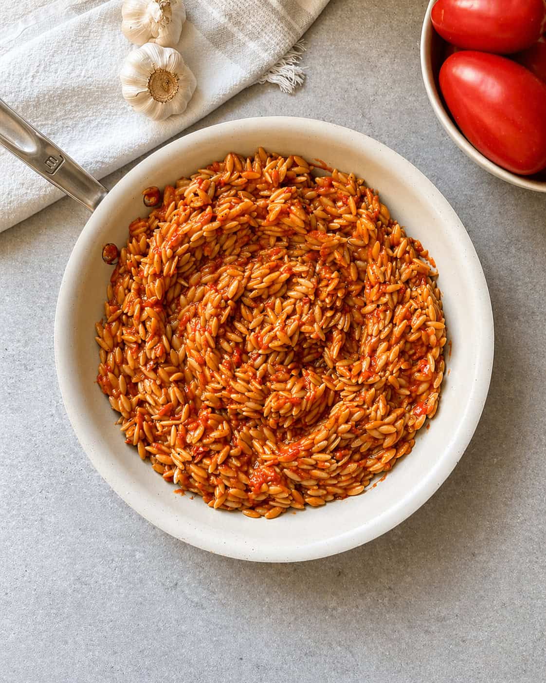 Tomato Orzo in a white frying pan that has been simmered with a chicken broth..