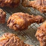 Close-up of several crispy, golden-brown drumsticks resting on a wire rack—perfect inspiration if you're looking for a Crispy Fried Chicken Recipe.