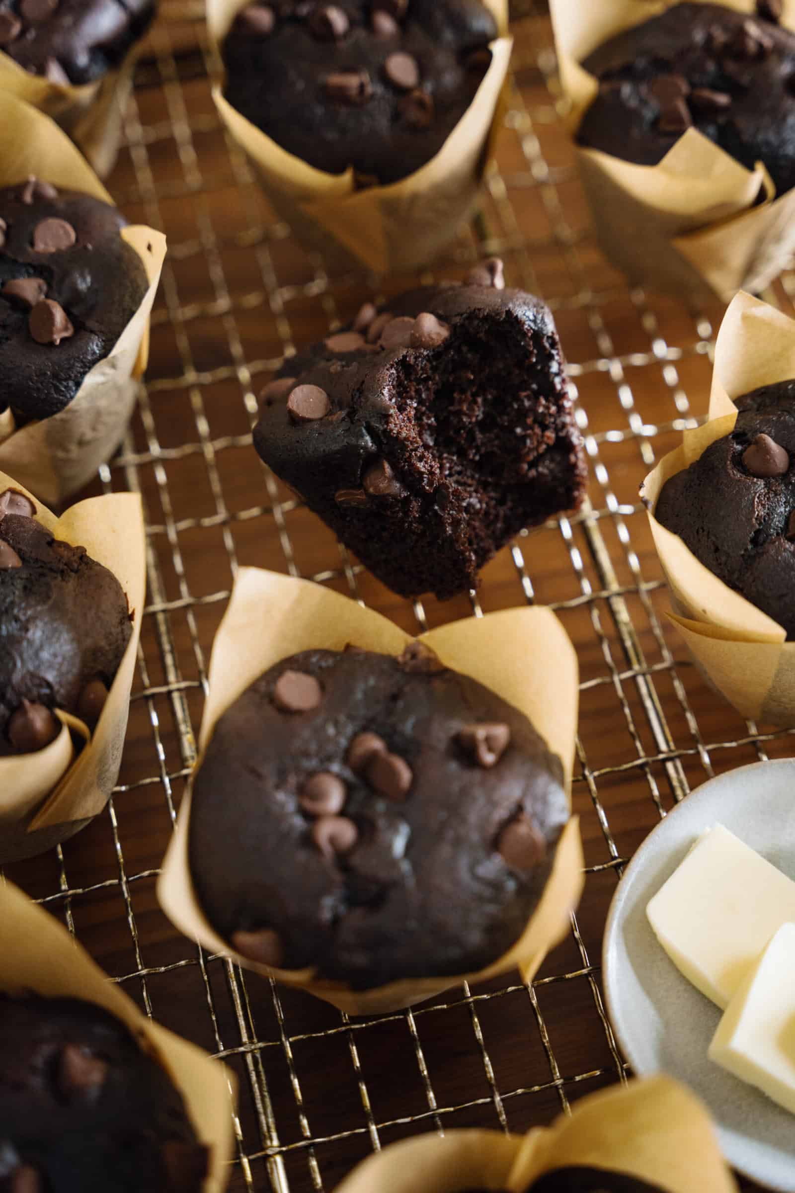 Rich chocolate cupcakes with chocolate chips on a cooling rack.