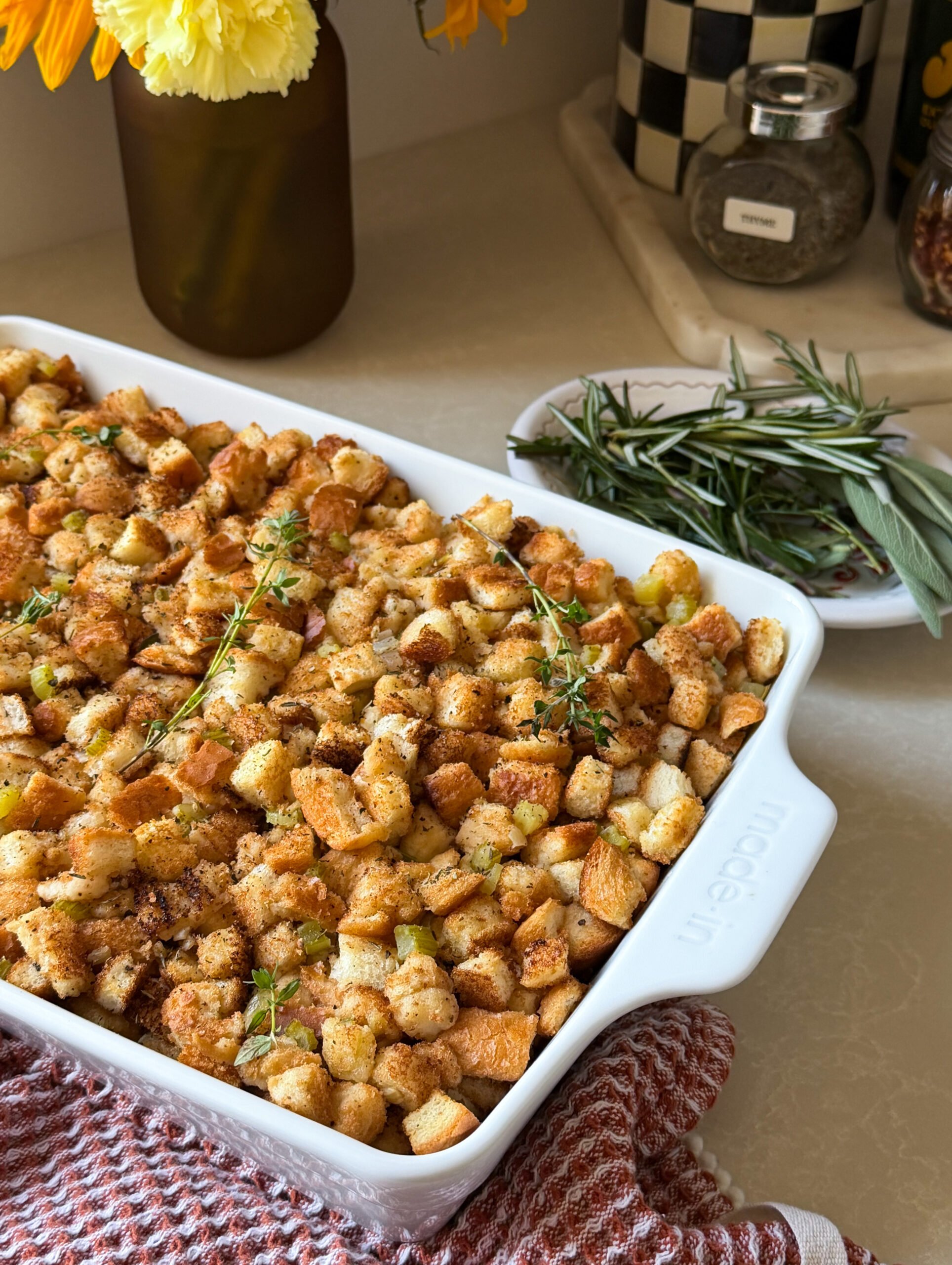 Crispy homemade croutons in a white baking dish, garnished with fresh herbs, on a cozy kitchen countertop.