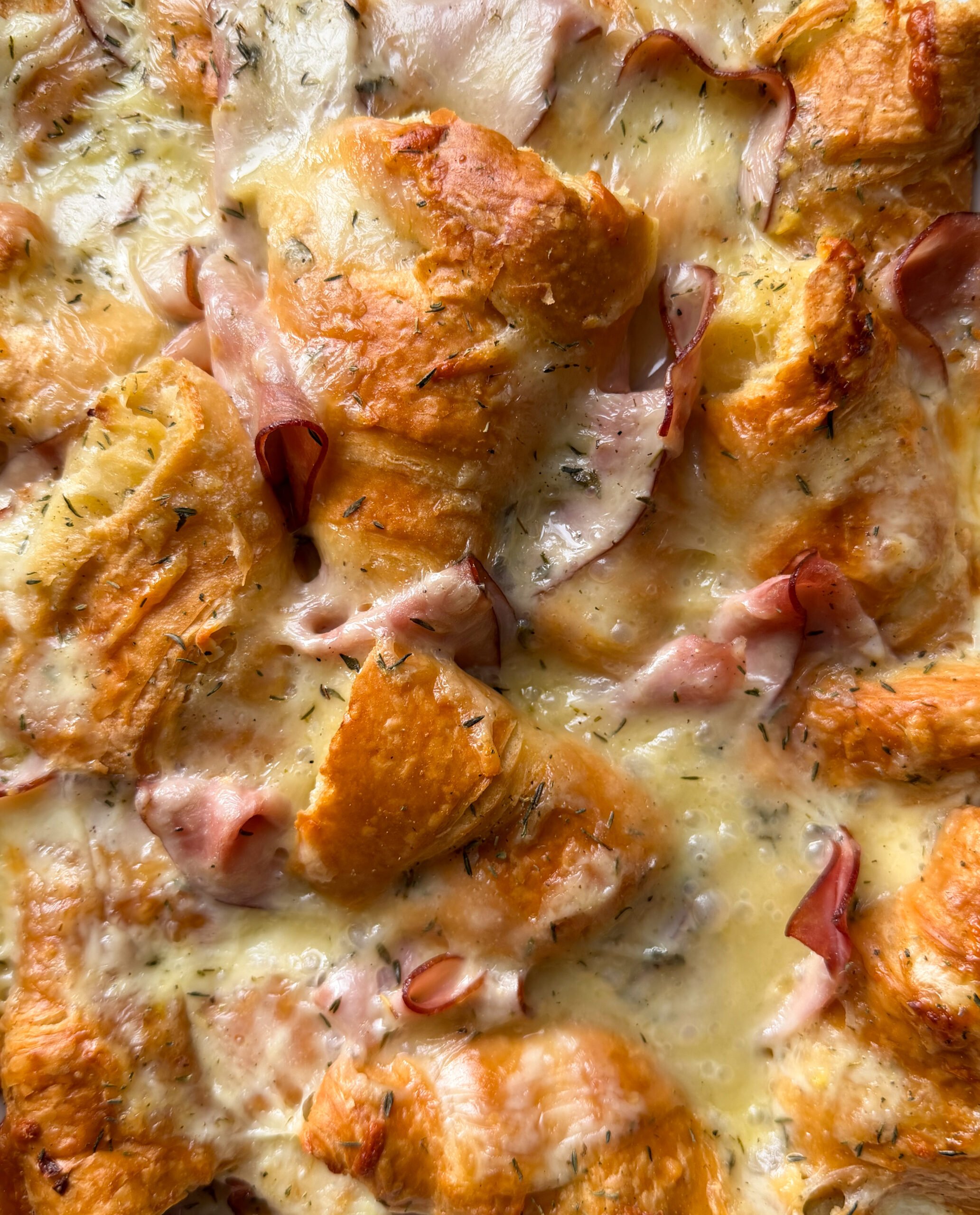 Golden, flaky croissant pieces baked with melted cheese, herbs, and slices of ham create a savory Ham and cheese croissant bake—an ideal Christmas morning breakfast.