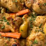 Close-up of maple mustard chicken pieces with golden-brown skin, baby potatoes, and carrot sticks, all garnished with chopped fresh parsley. A delectable sheet pan dinner idea that's well-seasoned and cooked to perfection.