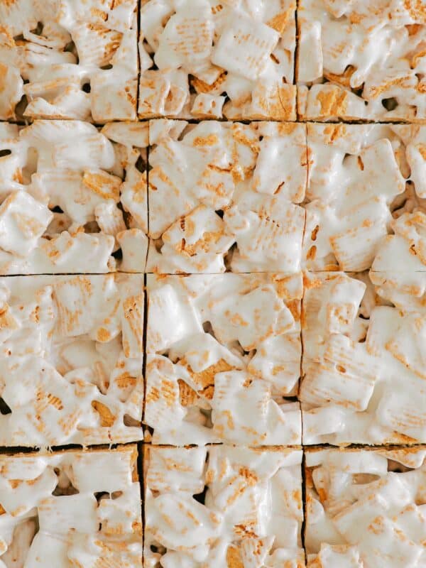 Close-up of Marshmallow Graham Squares made from frosted mini wheat cereal and golden grahams cereal, held together by a glossy, white marshmallow coating, arranged in a grid and cut into perfectly sized marshmallow treats.