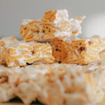 Squares made from frosted mini wheat cereal and golden grahams cereal, held together by a glossy, white marshmallow coating, arranged in a grid and cut into perfectly sized marshmallow treats.