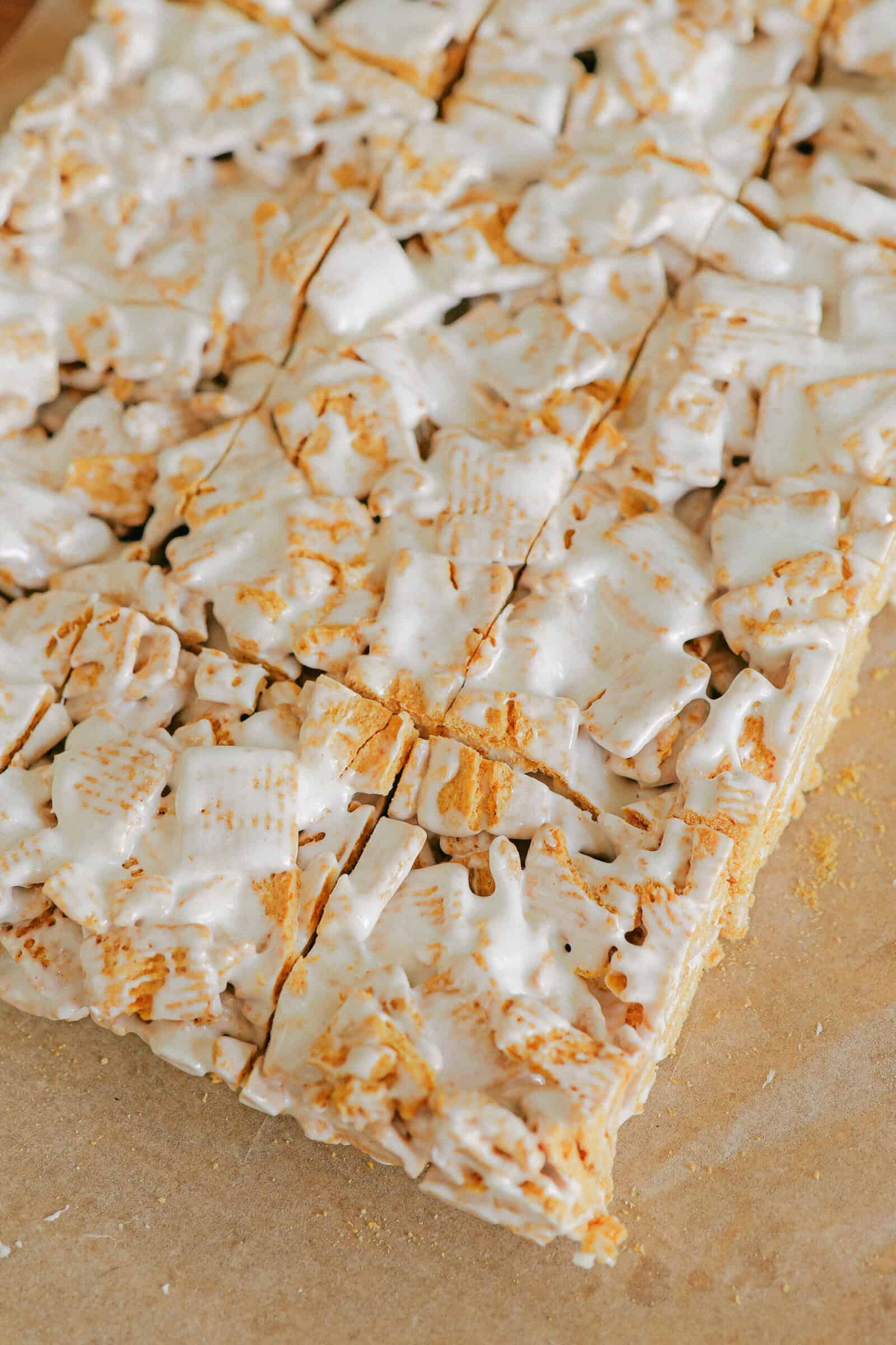 Squares made from frosted mini wheat cereal and golden grahams cereal, held together by a glossy, white marshmallow coating, arranged in a grid and cut into perfectly sized marshmallow treats.