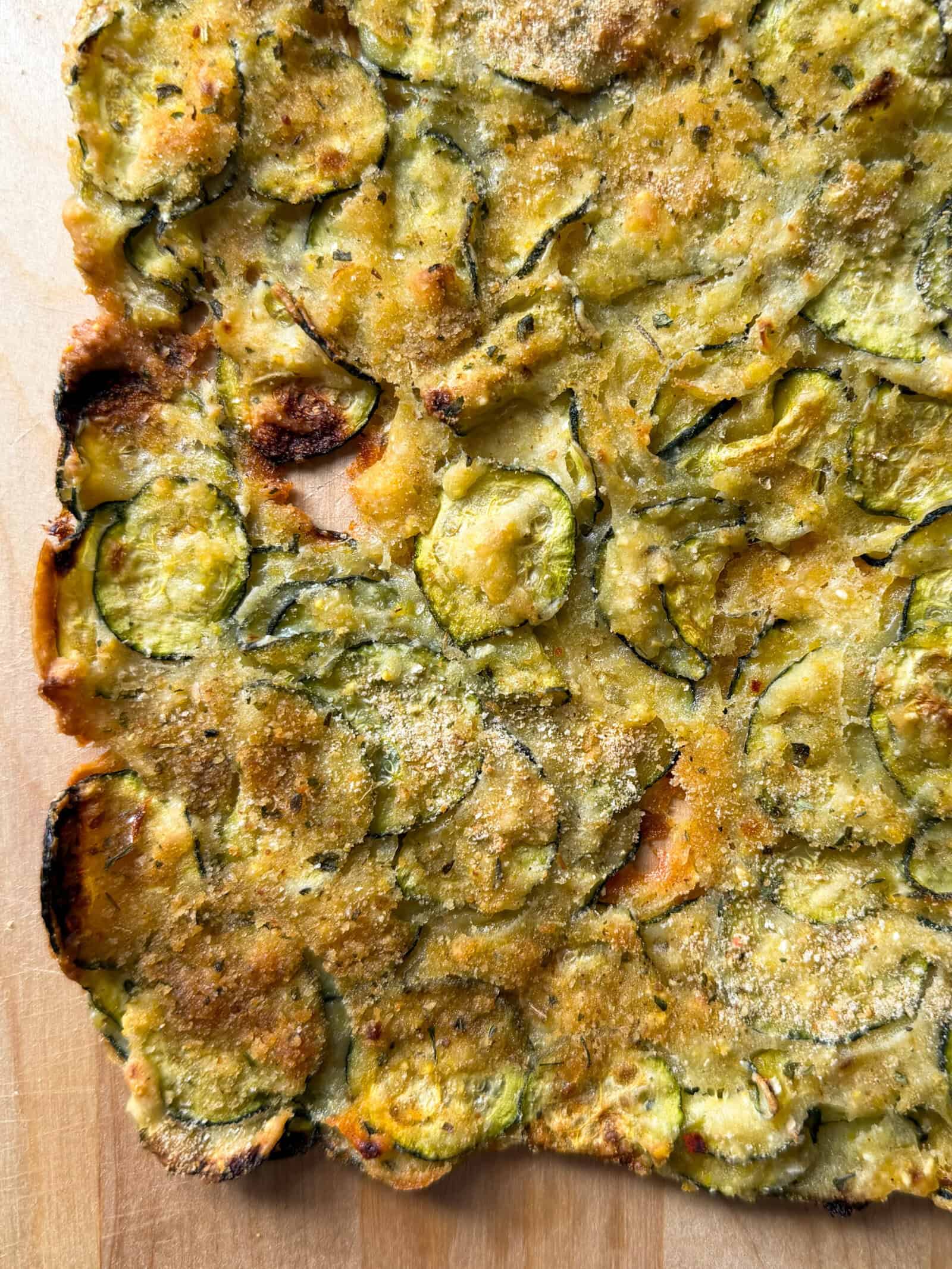 Golden, crispy Zucchini Flatbread inspired by the classic zucchini scarpaccia, topped with thinly sliced zucchini, fresh herbs, and a sprinkle of breadcrumbs. Its rustic texture and slightly browned edges make this a must-try zucchini flatbread recipe.
