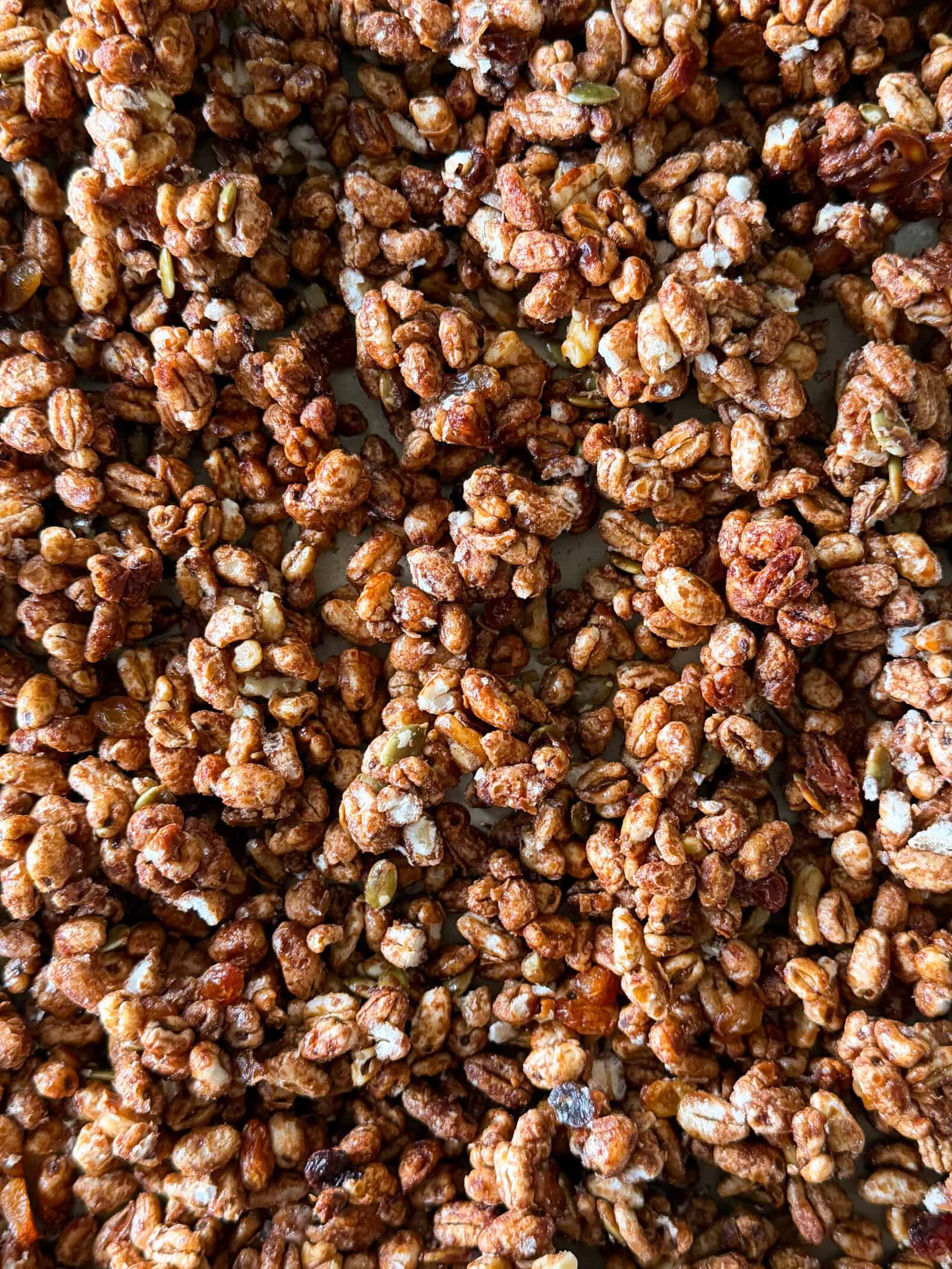 Close-up of crunchy, caramelized granola clusters with visible puffed grains and nuts mixed together—a delicious homemade cereal recipe perfect for breakfast or snacking.