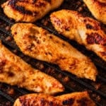 Yogurt marinated chicken tenderloins cooking on a ridged grill pan.