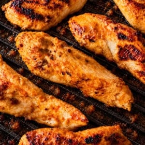 Yogurt marinated chicken tenderloins cooking on a ridged grill pan.